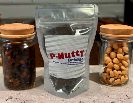 P-Nutty Brickle Bag on counter with raisins and peanuts in jars