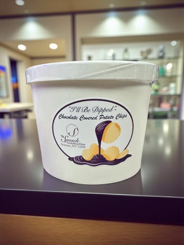 container of chocolate covered potato chips on a black counter in a store