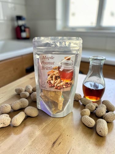 Maple Peanut Brittle Bag on a counter with maple syrup and peanuts