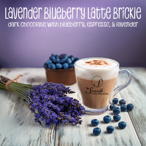 Lavender Blueberry Latter Brickle label - spray of fresh lavender, fresh blueberries and a latte in clear coffee cup on white wooden counter with purple background
