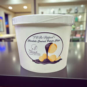 container of chocolate covered potato chips on a black counter in a store