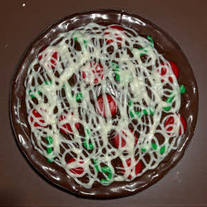 Milk chocolate personal pan potato chip pizza with red "pepperoni" and green "peppers" on a brown countertop