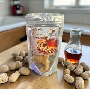 Maple Peanut Brittle Bag on a counter with maple syrup and peanuts